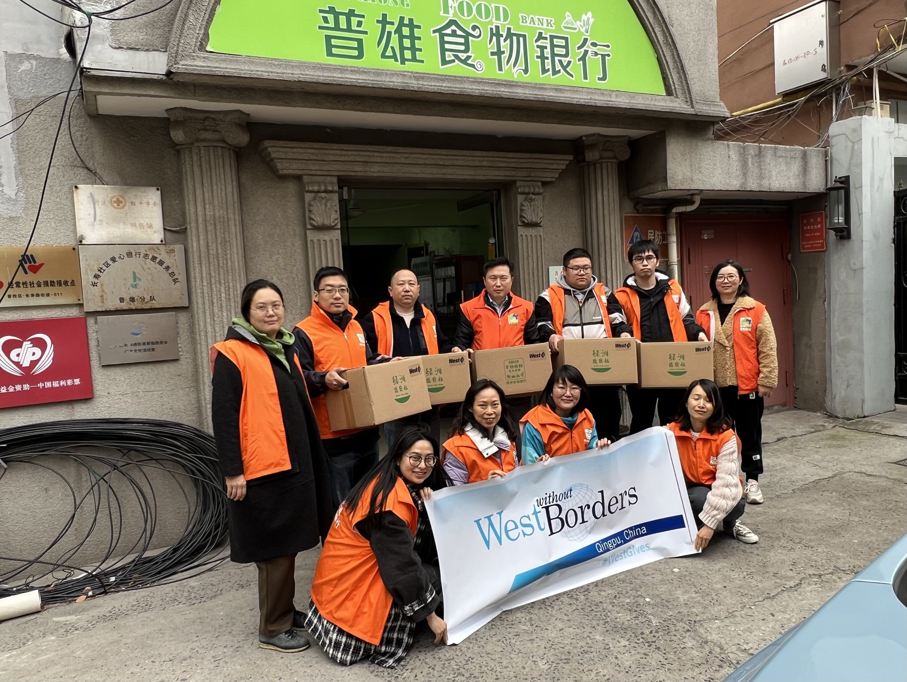 A group of West employees holding boxes of food collected from their food drive