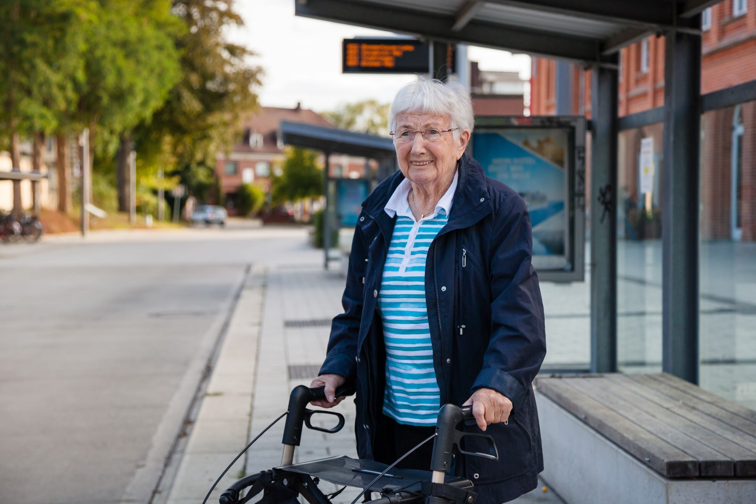 An elderly woman with deteriorating vision waiting at a bus station