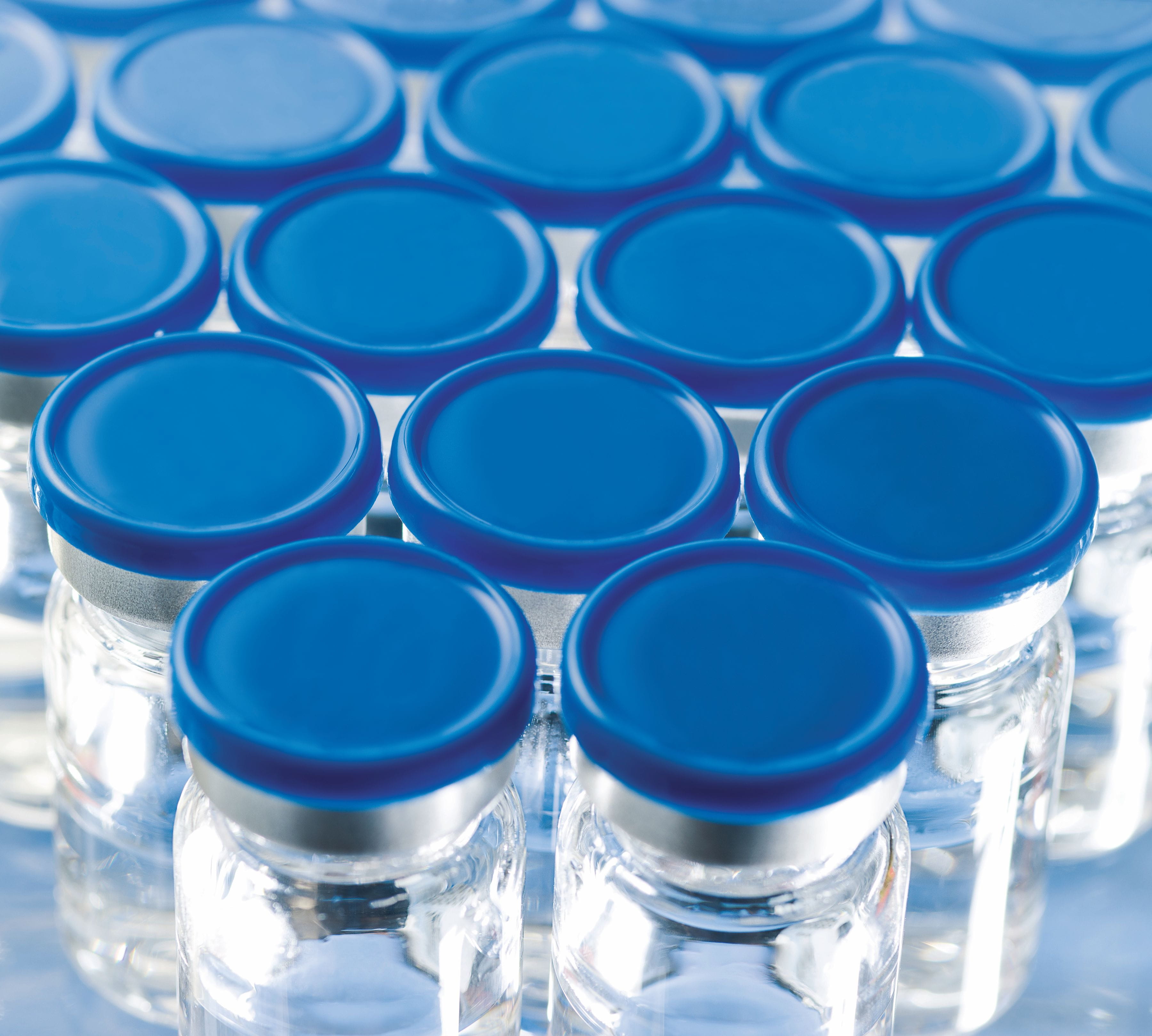 Glass vials with blue stoppers for parenteral drug packaging.