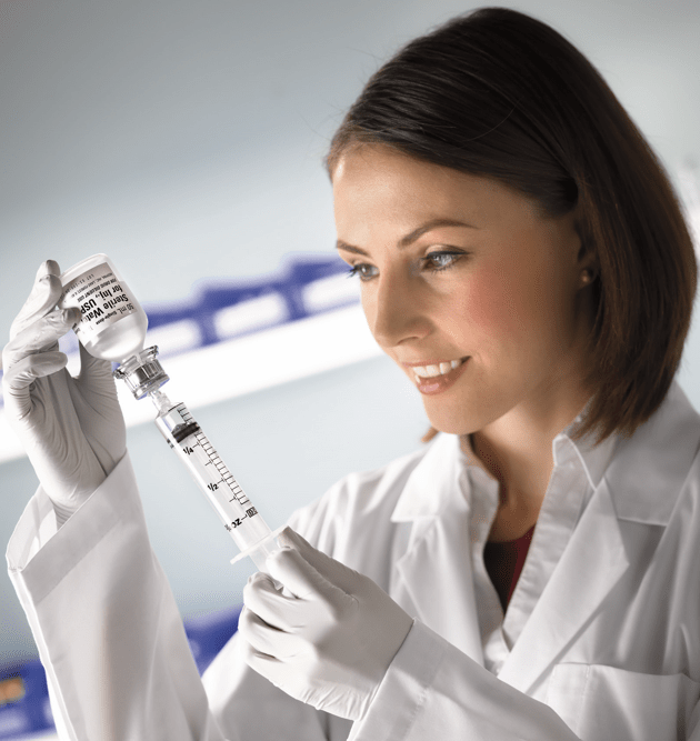 Lab professional filling a syringe from a vial.